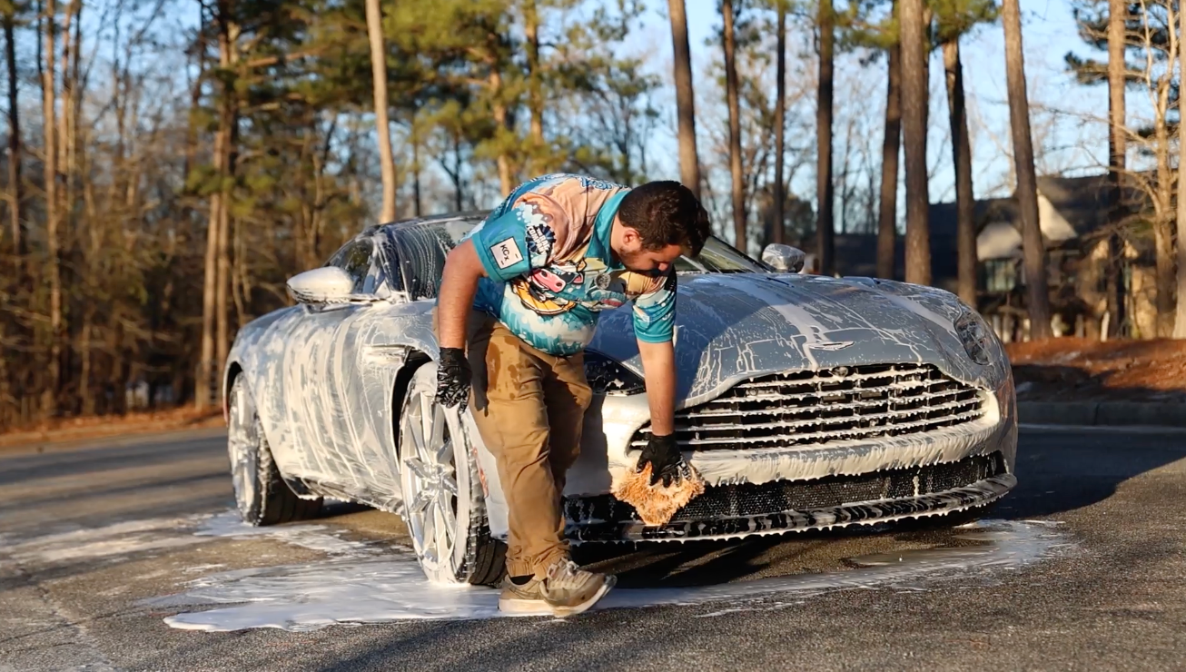 A man is cleaning the back of a car with a vacuum cleaner.