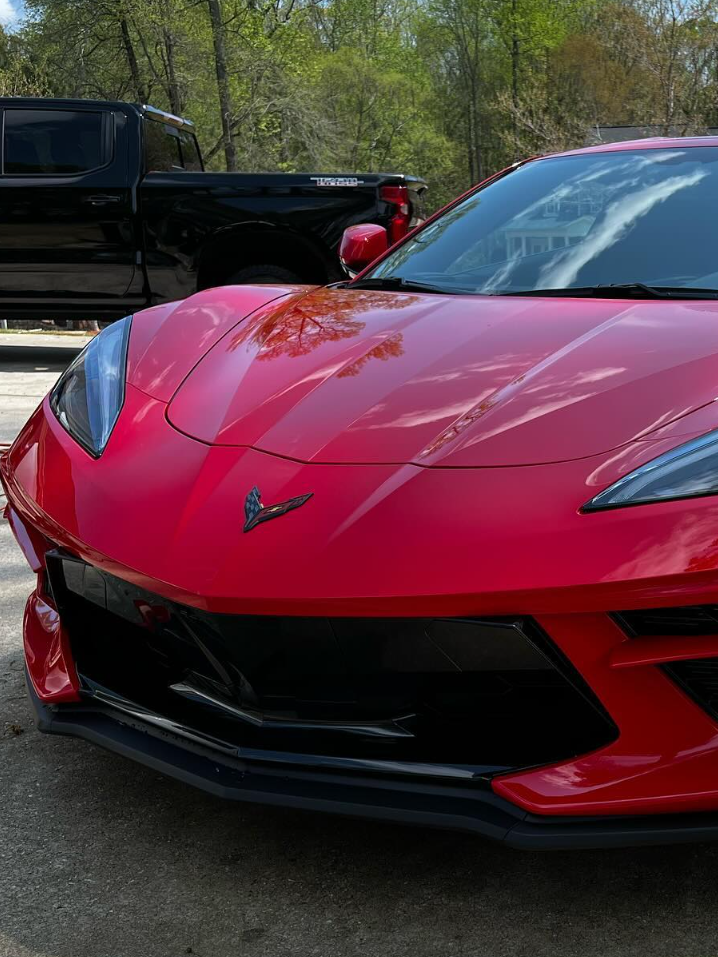 A white bmw is parked on a gravel road in a park.