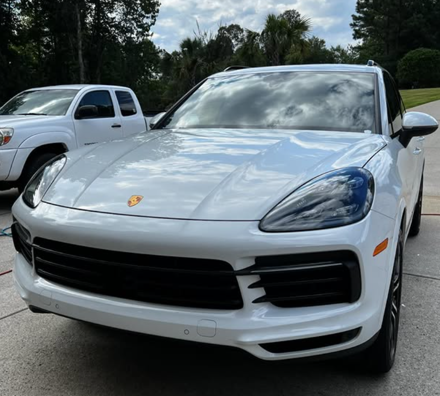 A close up of a car headlight with water drops on it.