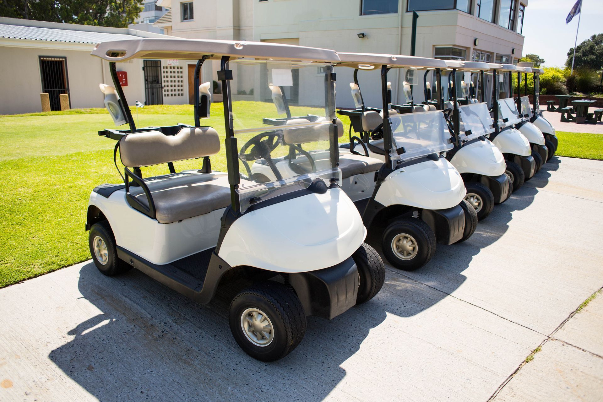 A row of golf carts are parked on the sidewalk