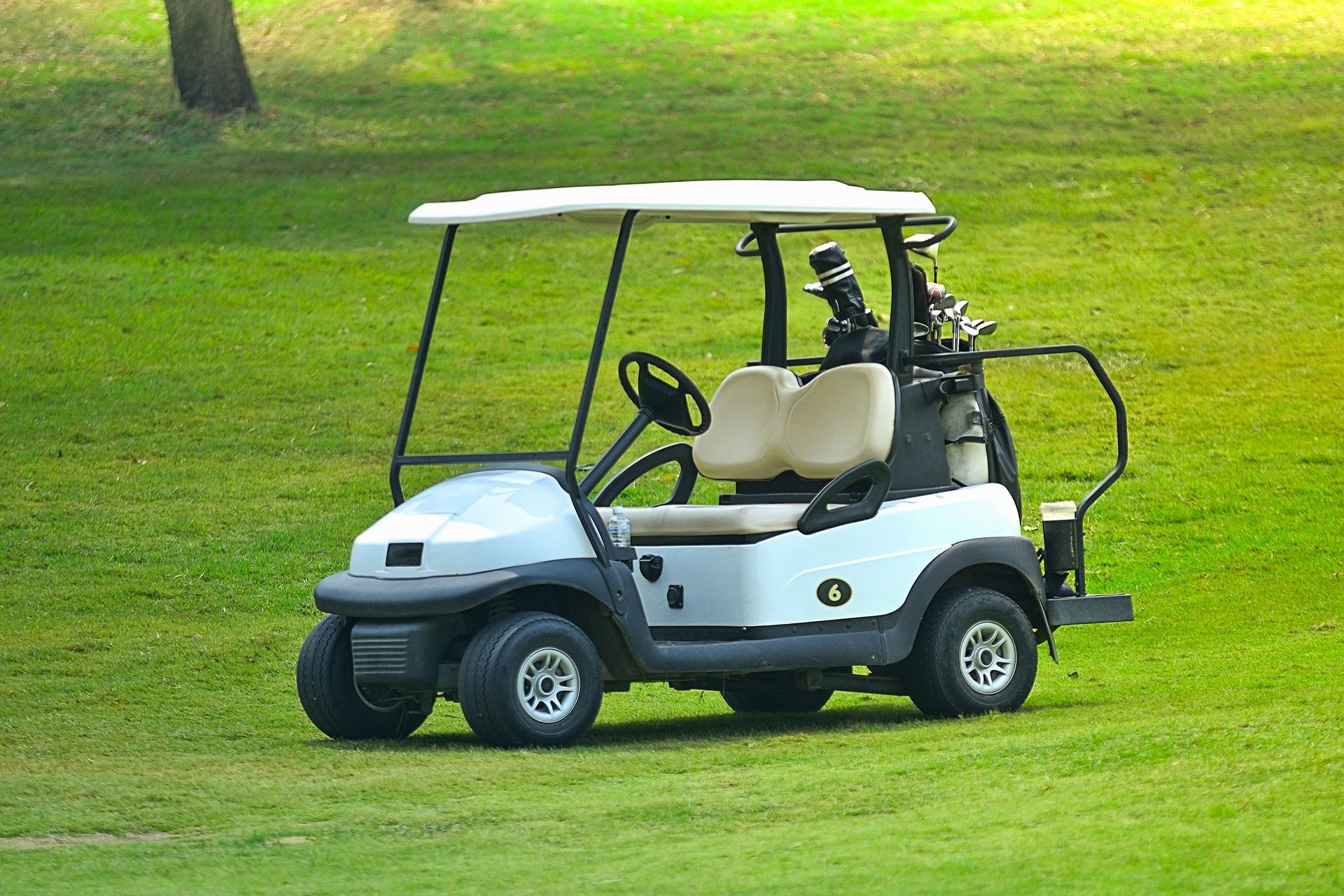 A white golf cart is parked on a lush green golf course.
