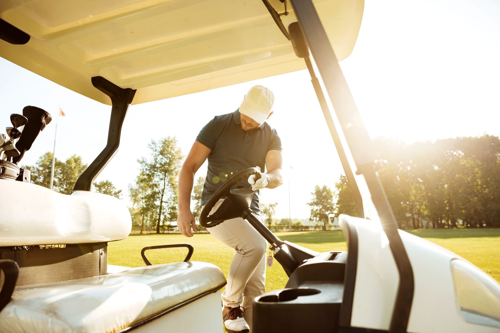 A man is sitting in a golf cart on a golf course.