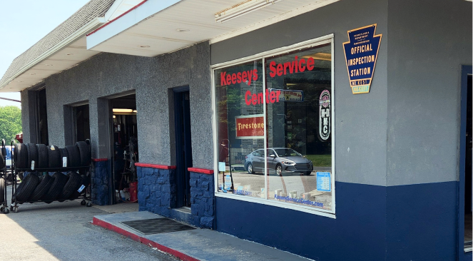 Keny's Service Center, a gray and blue auto repair shop, with tires for sale outside.