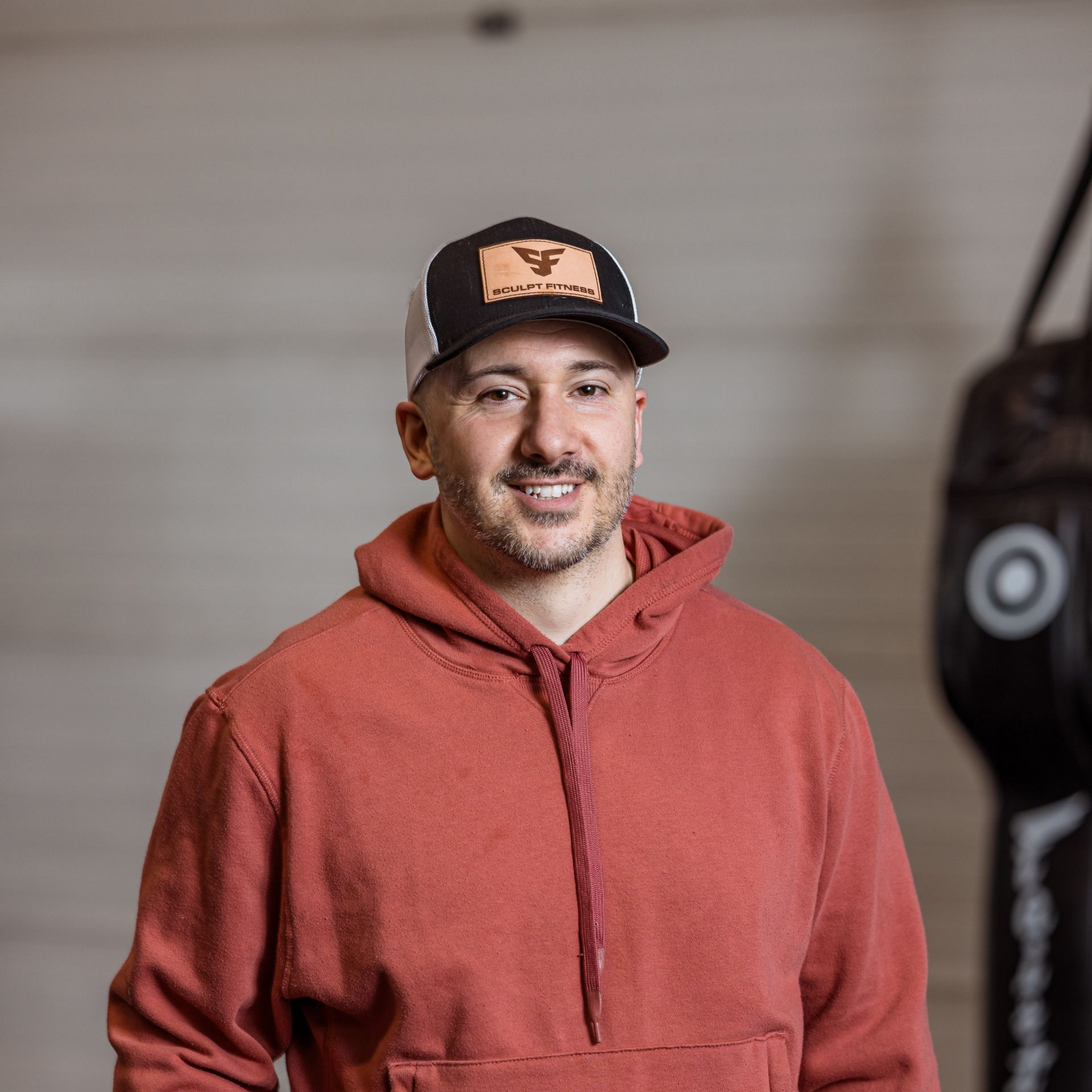 Three women in workout clothes stand in a gym.