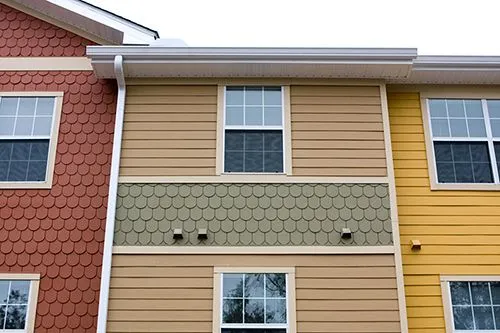 A row of houses with different colored siding and windows