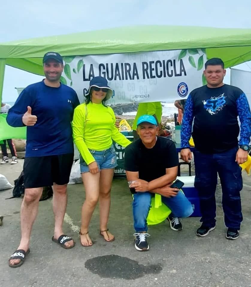 Two men smiling, one making a peace sign, in front of a mirrored food stall with the name "TAKE A NGER".
