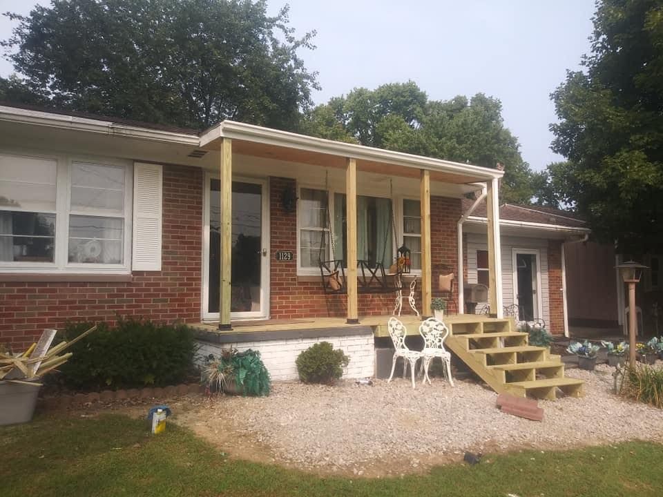 Newly constructed covered porch with steps, white trim, and light gravel landscaping.