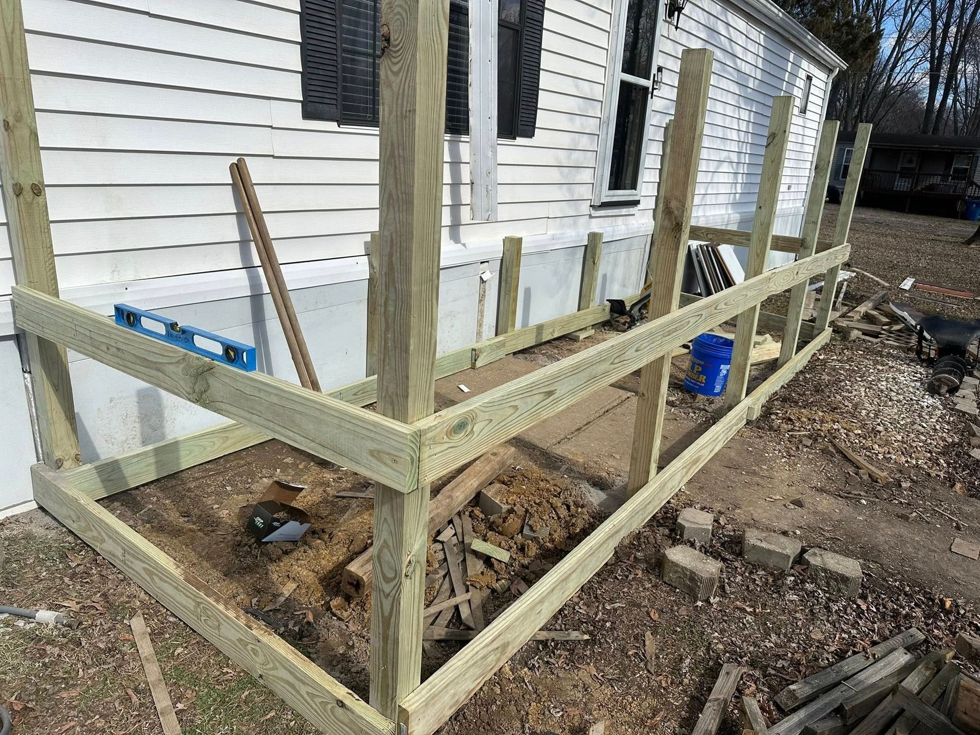 Wooden deck frame under construction against a white house.