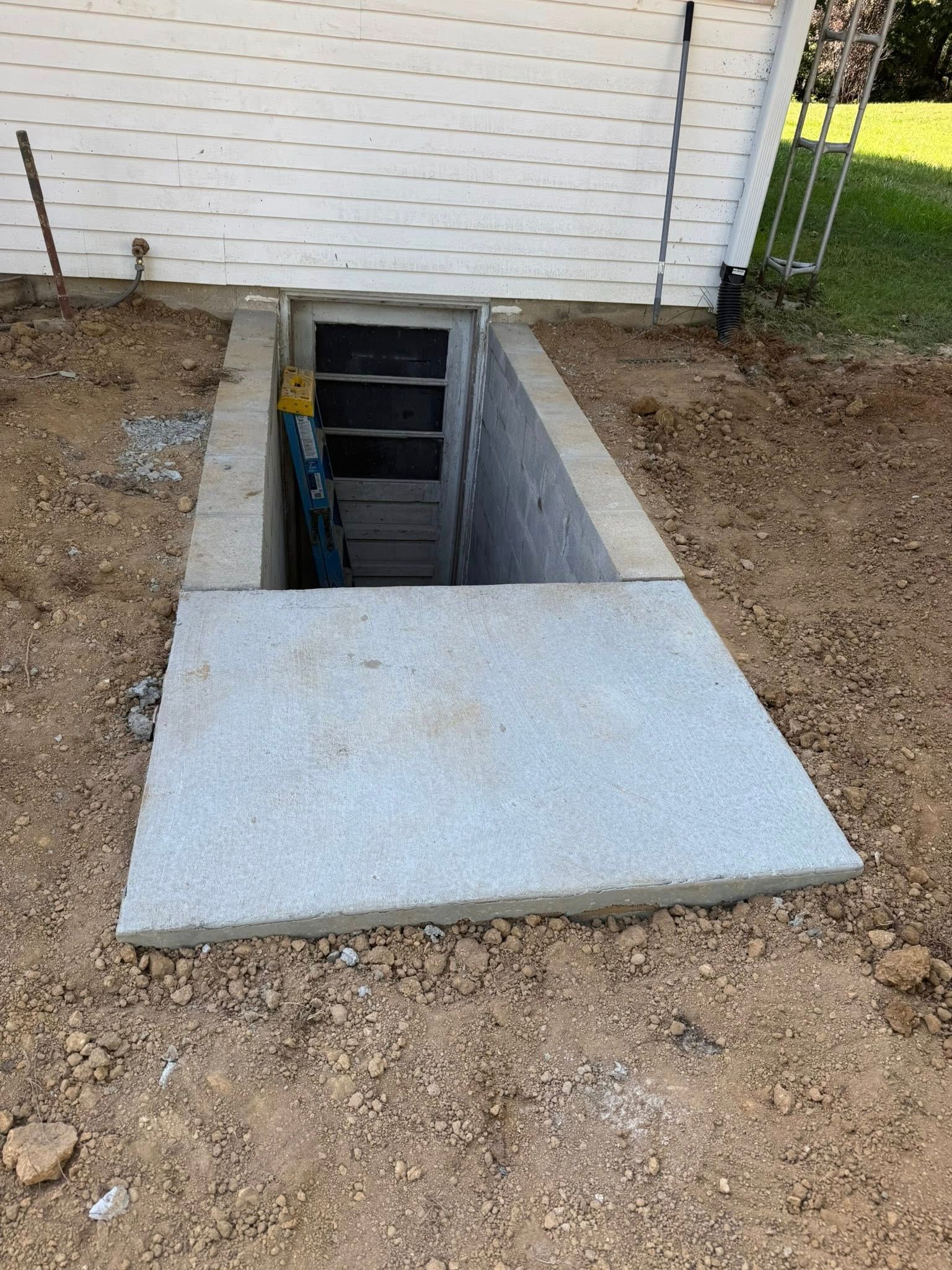 Concrete basement door entrance with a raised concrete slab cover.