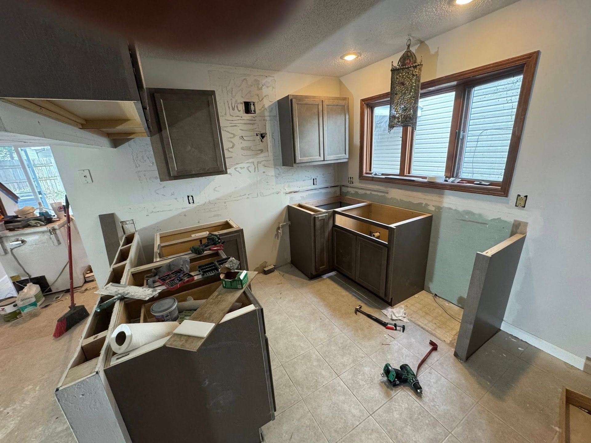 Kitchen renovation in progress: cabinets installed, walls unfinished, tools scattered.