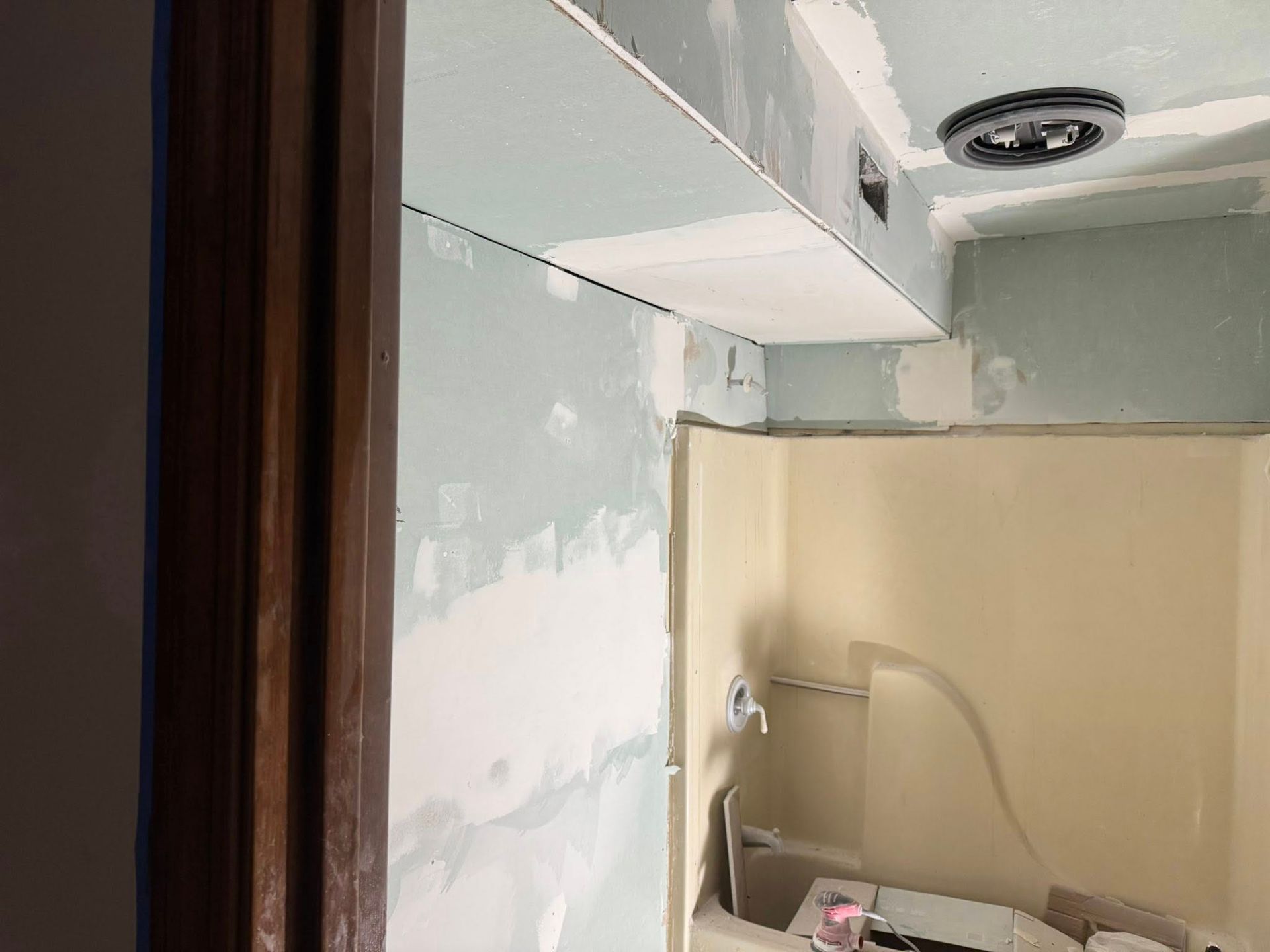 Bathroom renovation in progress, featuring drywall on walls and ceiling, shower stall.
