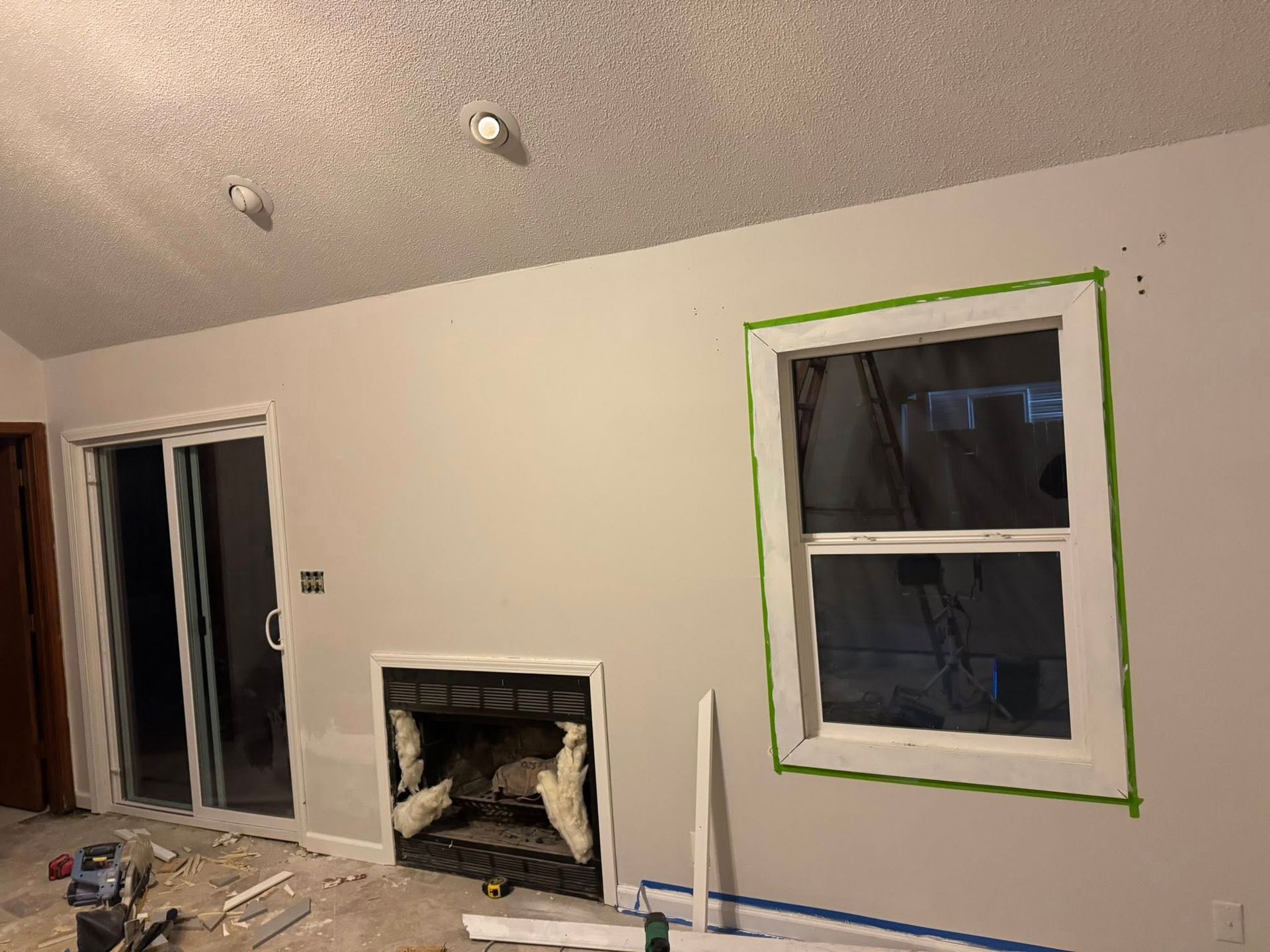 Interior view of a room with a window and fireplace. The window has green tape around the edges.