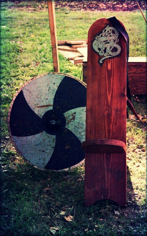 Round shield and wooden medieval-style display board standing outdoors on grass