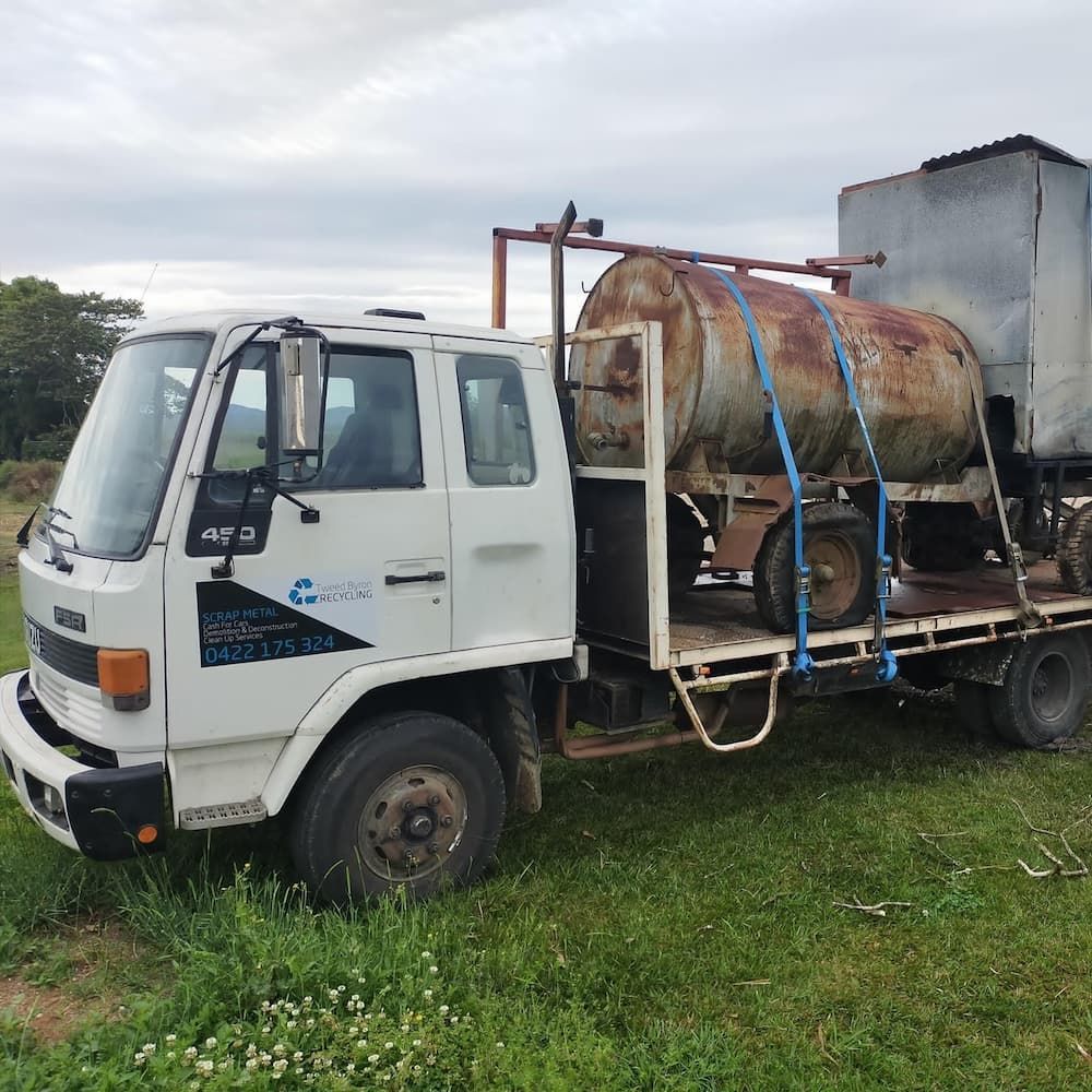 A White Truck With A Large Tank On The Back Is Parked In A Grassy Field — East Coast Metal Recycling In Logan, QLD