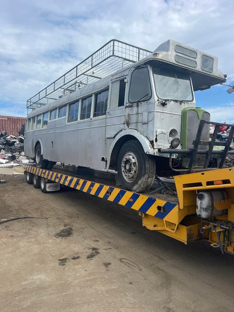 An Old Bus Is Being Towed By A Tow Truck — East Coast Metal Recycling In Tugun, QLD