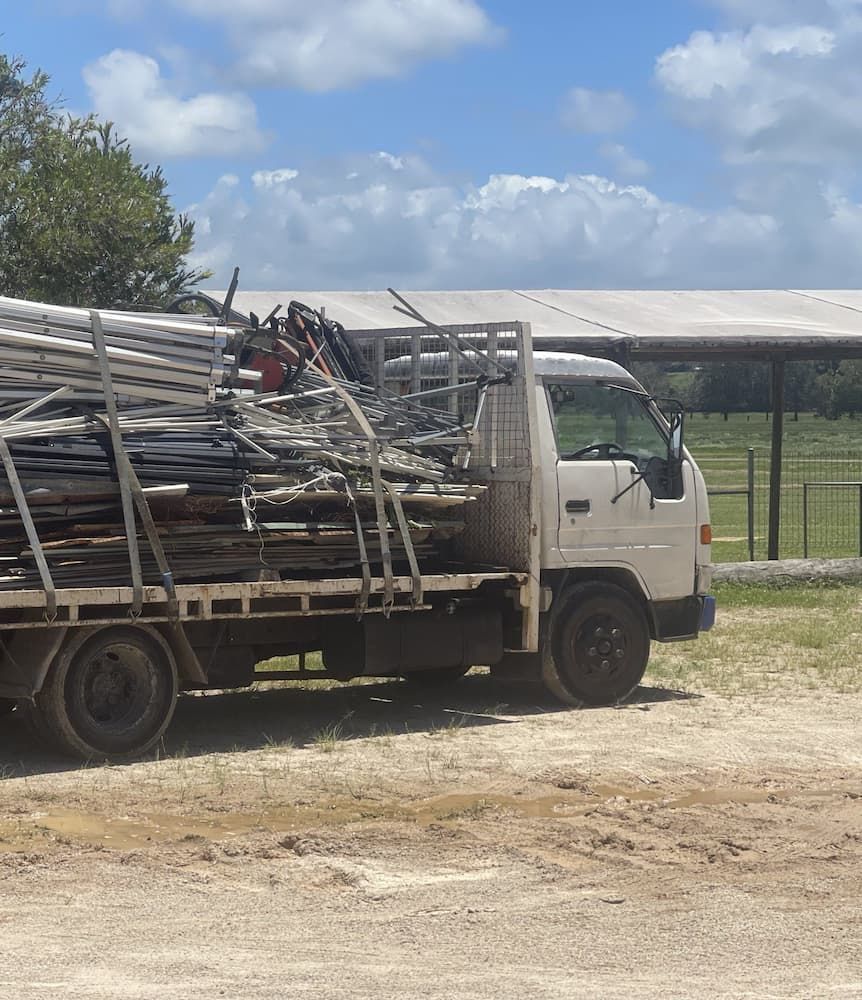 A White Truck With A Cage On The Back Is Parked In A Dirt Lot — East Coast Metal Recycling In Brisbane, QLD