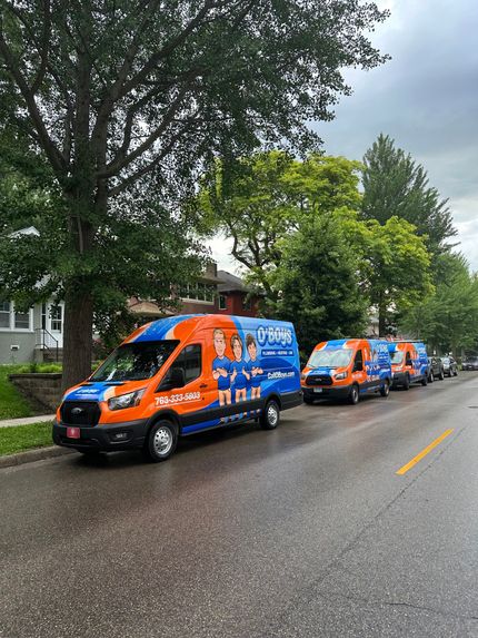 A row of orange and blue vans are parked on the side of a street.