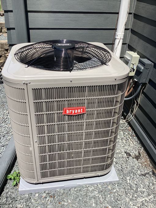 An air conditioner is sitting on the side of a house.