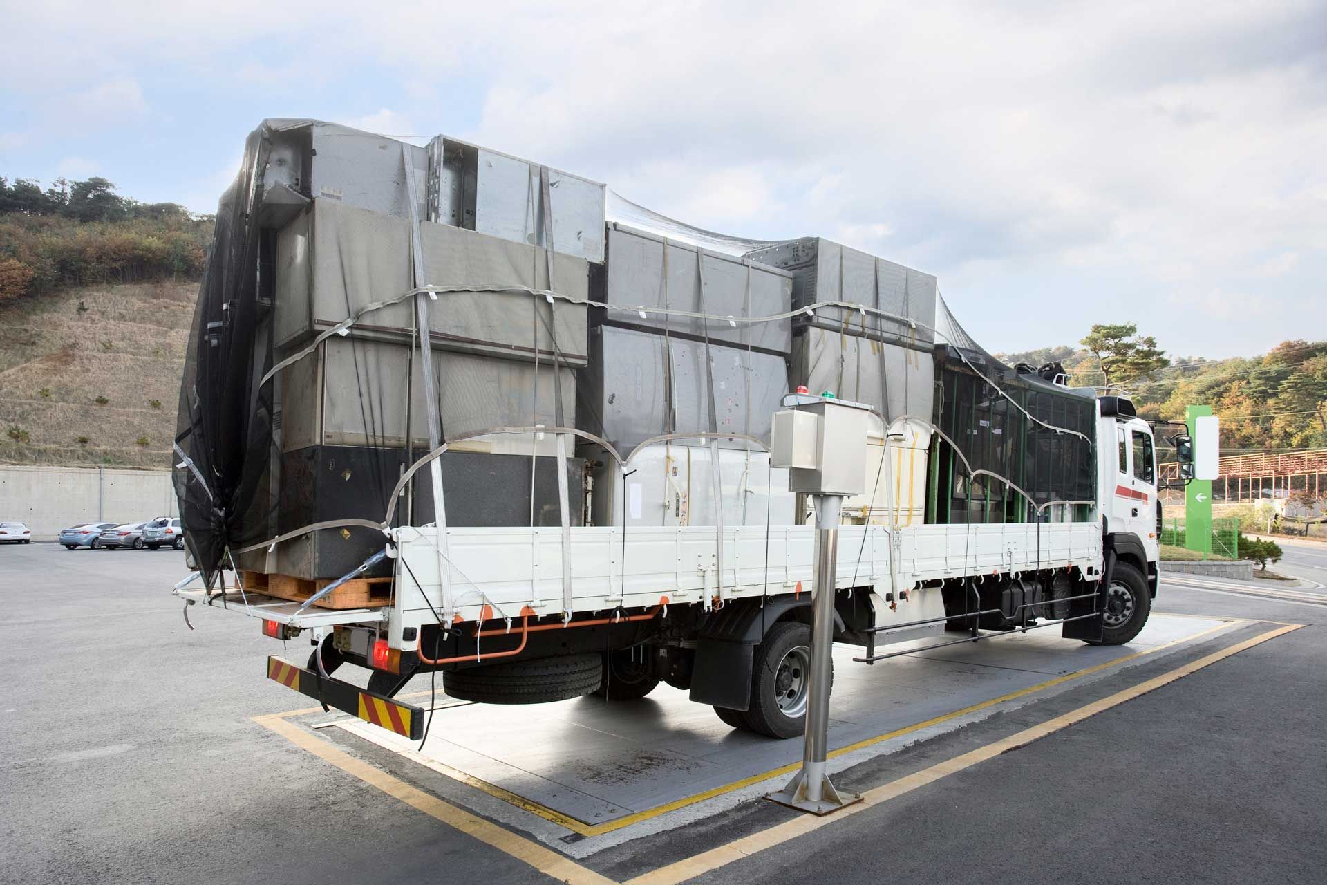 The container truck is on a scale that indicates the weight of the cargo being transported.