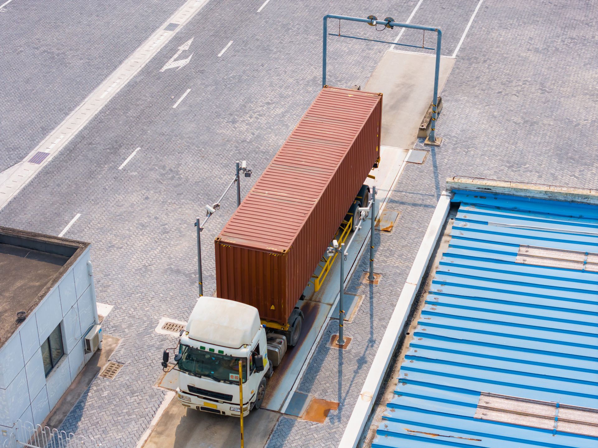 Overhead view of a truck with red container on a scale in an industrial area. Overhead view of a truck with red container on a scale in an industrial area.