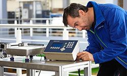 A man in a blue jacket is working on a machine.