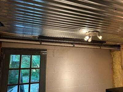 Corrugated metal ceiling, white brick wall, and a multi-bulb light fixture. A door with a window is on the left.