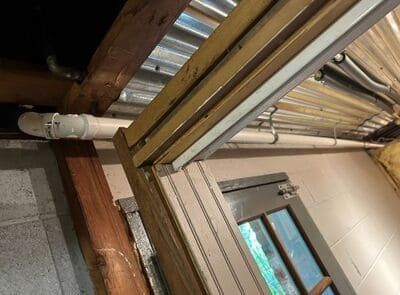 Plumbing pipes and a fluorescent light are installed on a ceiling.