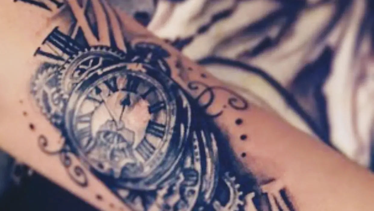 A person has a tattoo of a pocket watch on their arm