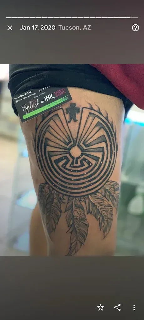 A person has a tattoo of a dream catcher on their thigh.