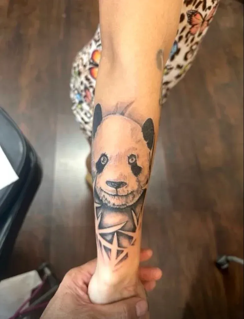 A person has a panda bear tattoo on their arm