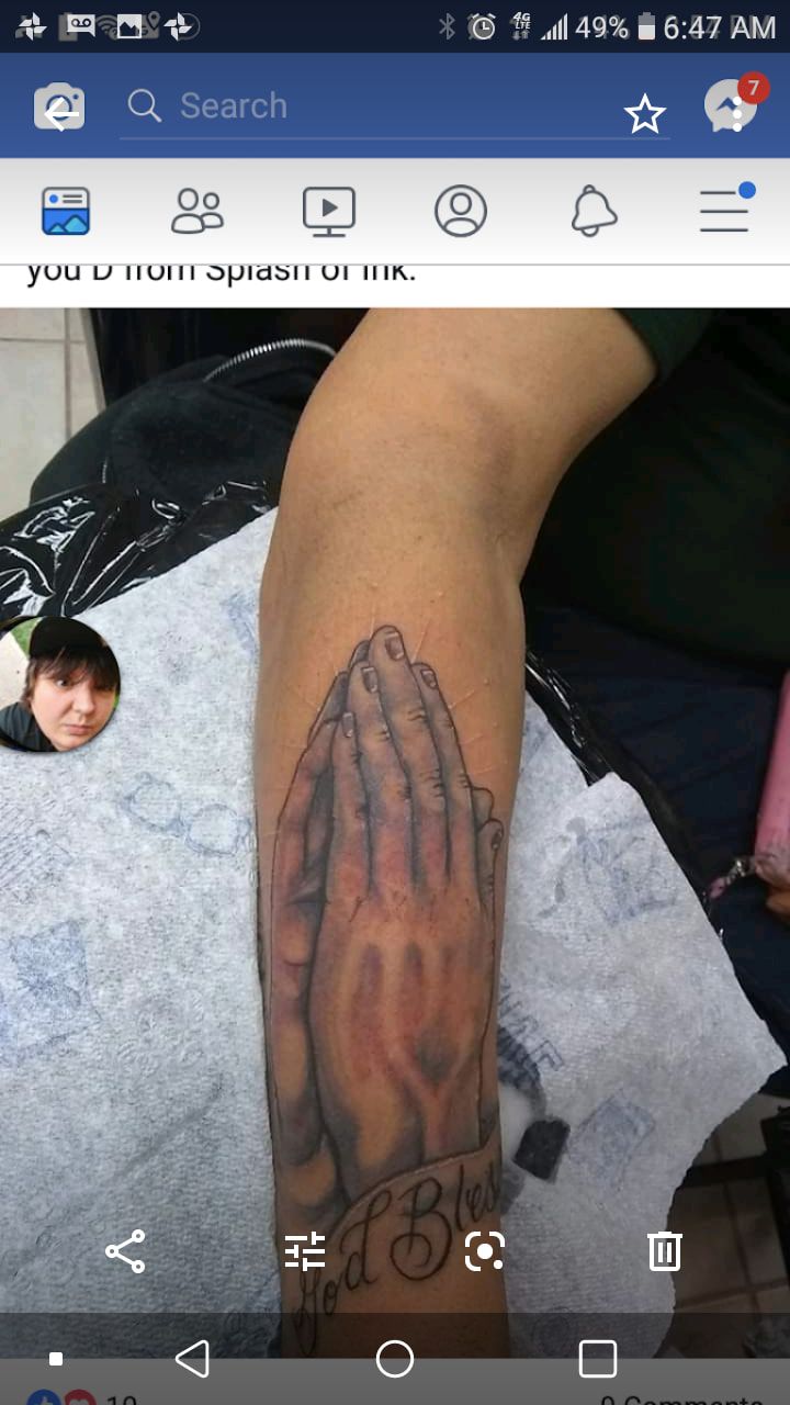 A person has a tattoo of praying hands on their arm