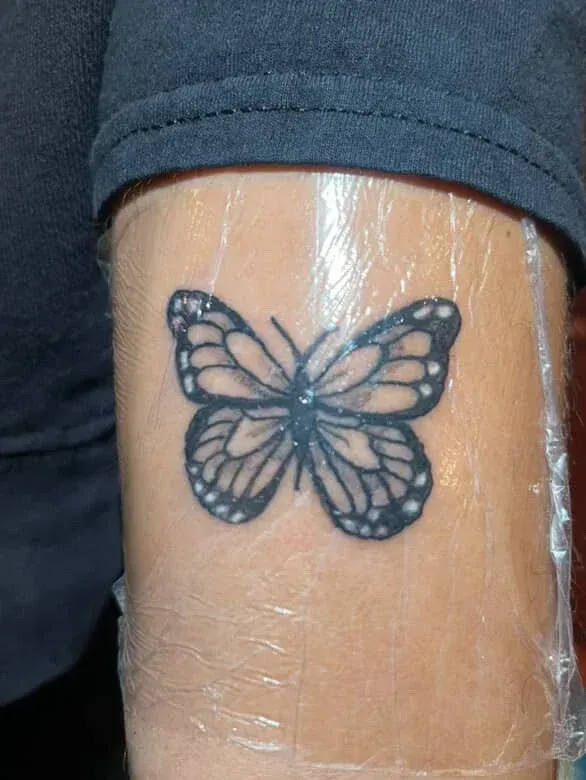 A person has a small butterfly tattoo on their wrist.
