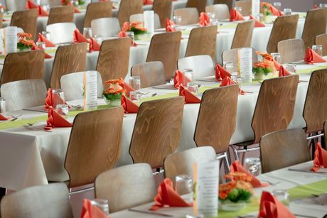 Rows of tables set for a catered event, with white tablecloths, red napkins, and floral centerpieces.