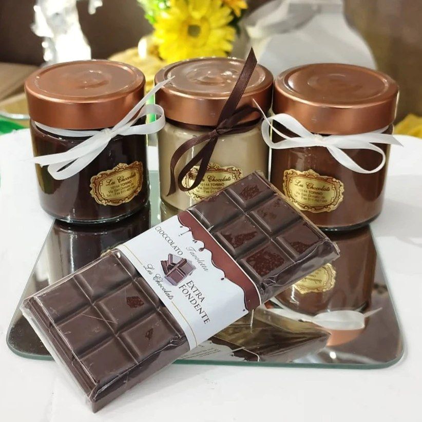 Barattoli di cioccolato con nastro e una tavoletta di cioccolato fondente su uno specchio.