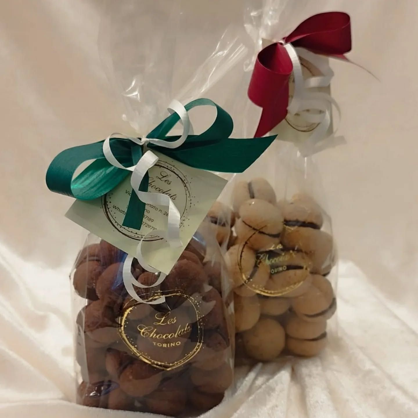 Due sacchetti di cellophane pieni di biscotti legati con nastri: uno verde e uno rosso.