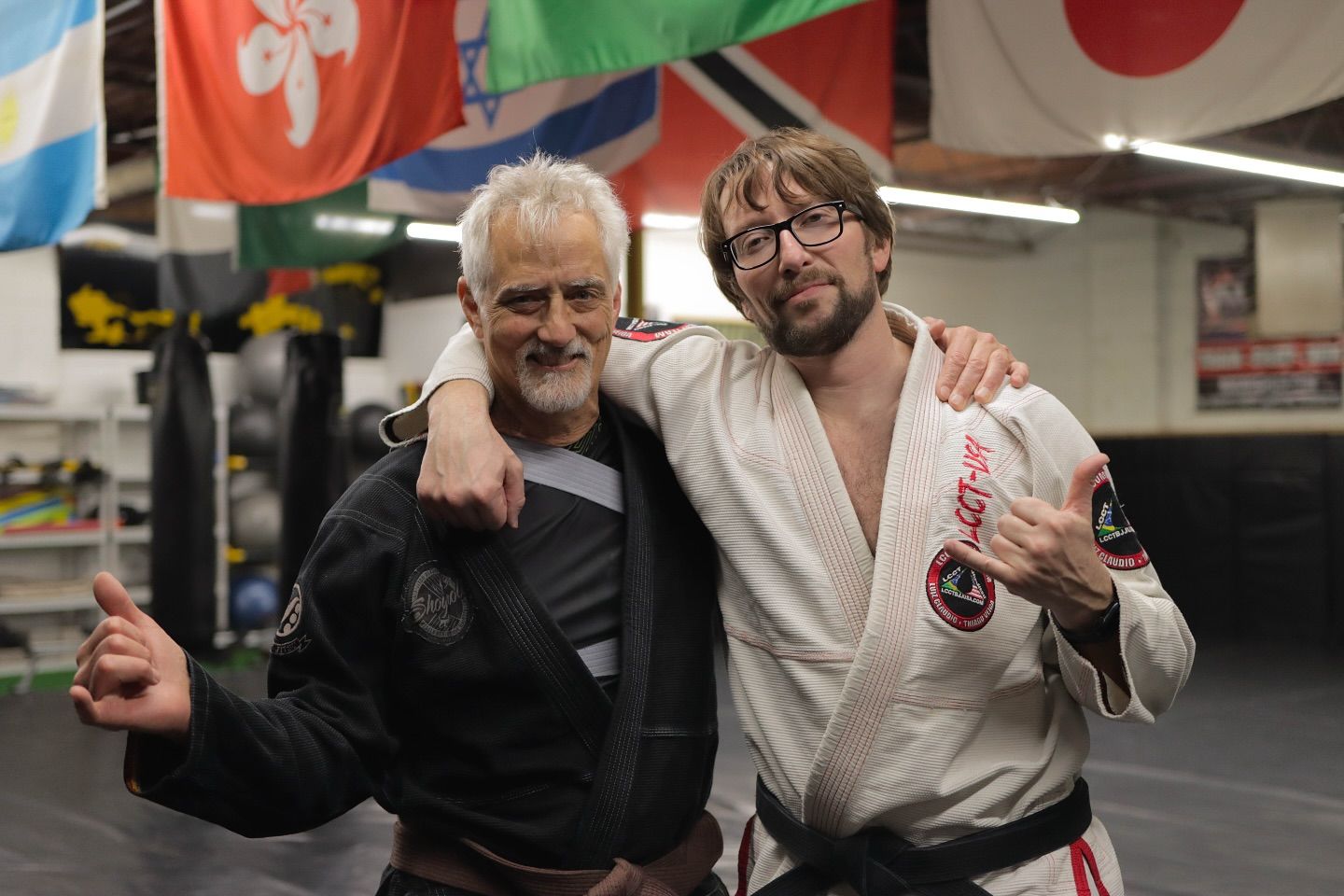 Two men in karate uniforms are posing for a picture in a gym.