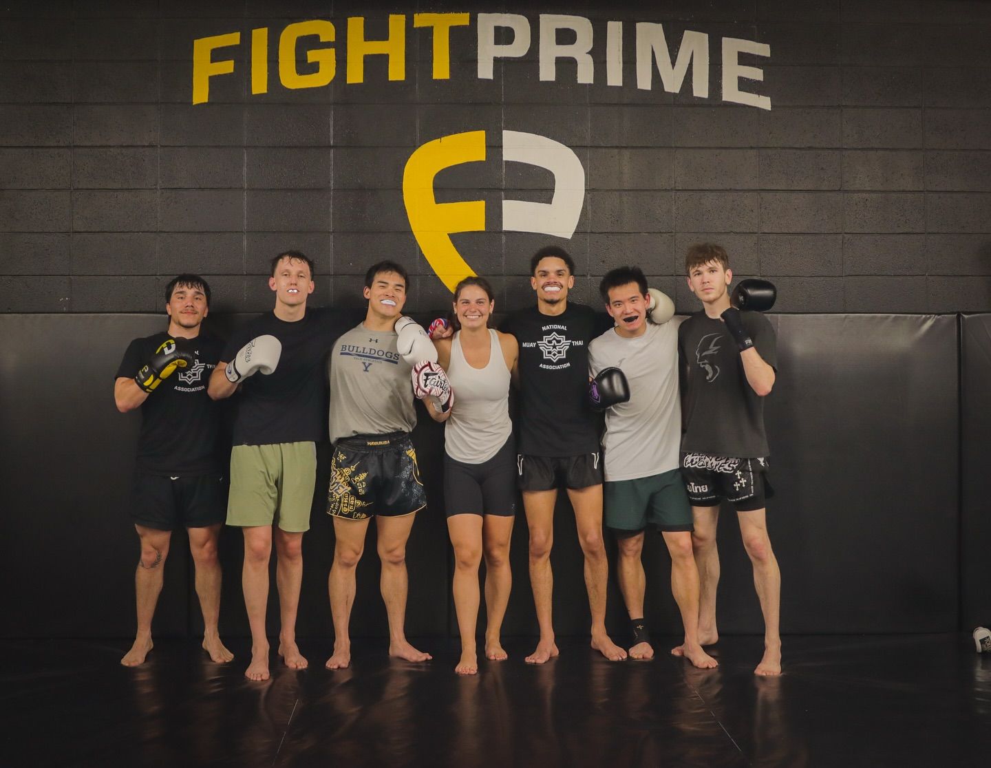 A group of people are posing for a picture in front of a wall that says fight prime