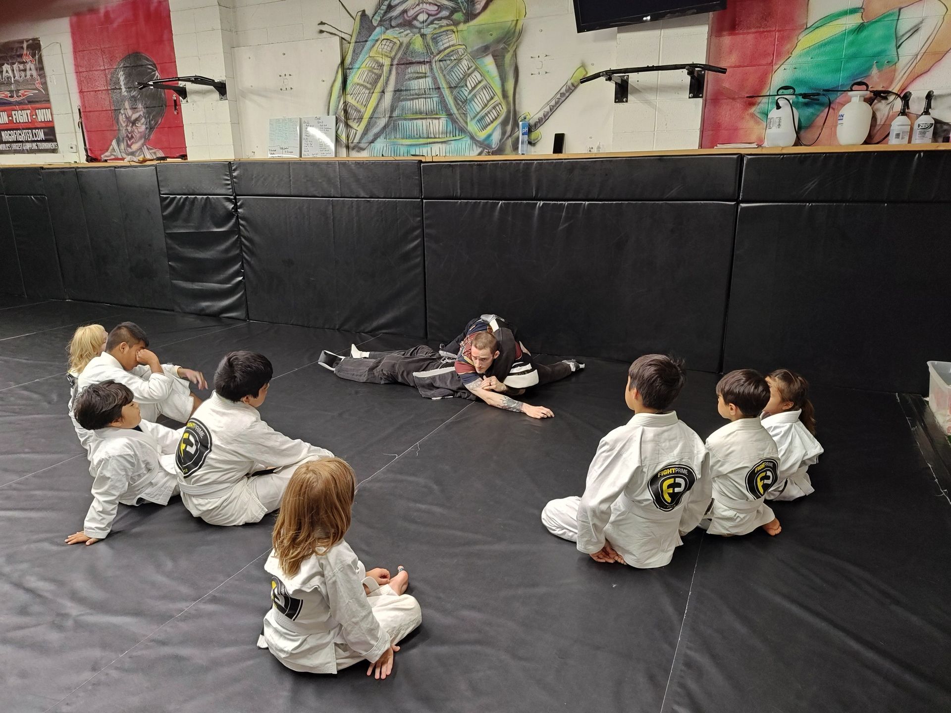 A group of children are sitting on a mat in a gym.
