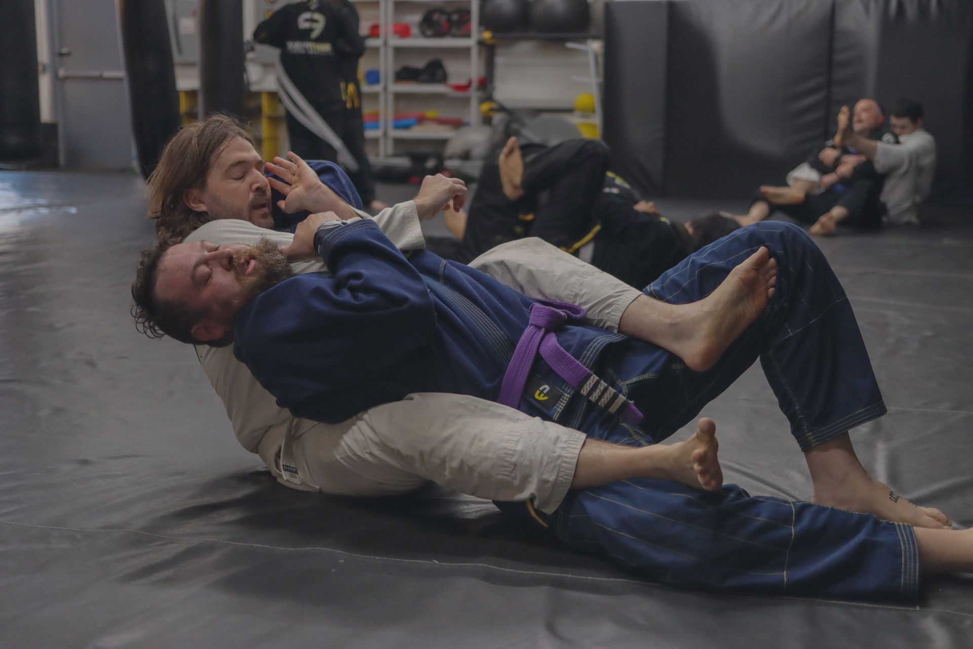 A group of people are practicing jiu jitsu in a gym.