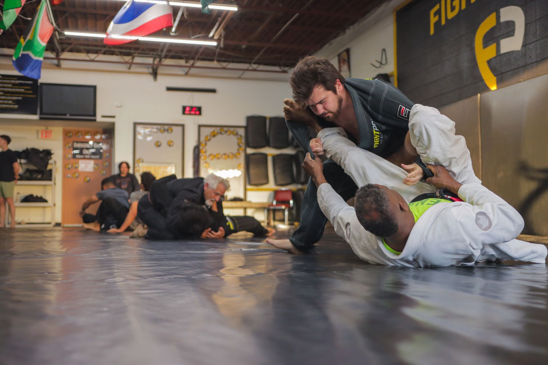 A group of people are practicing jiu jitsu in a gym.
