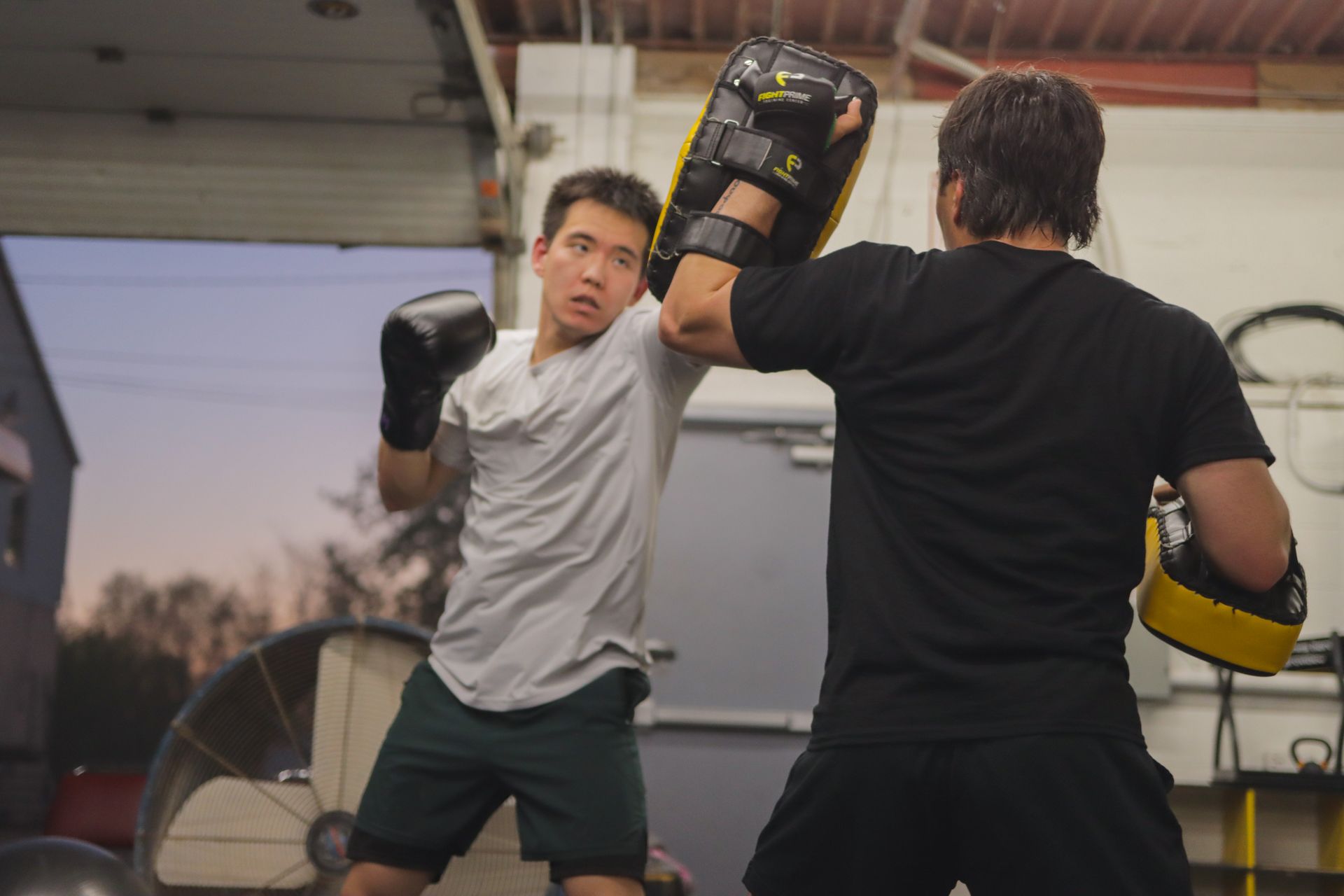 Two men are practicing boxing in a gym.