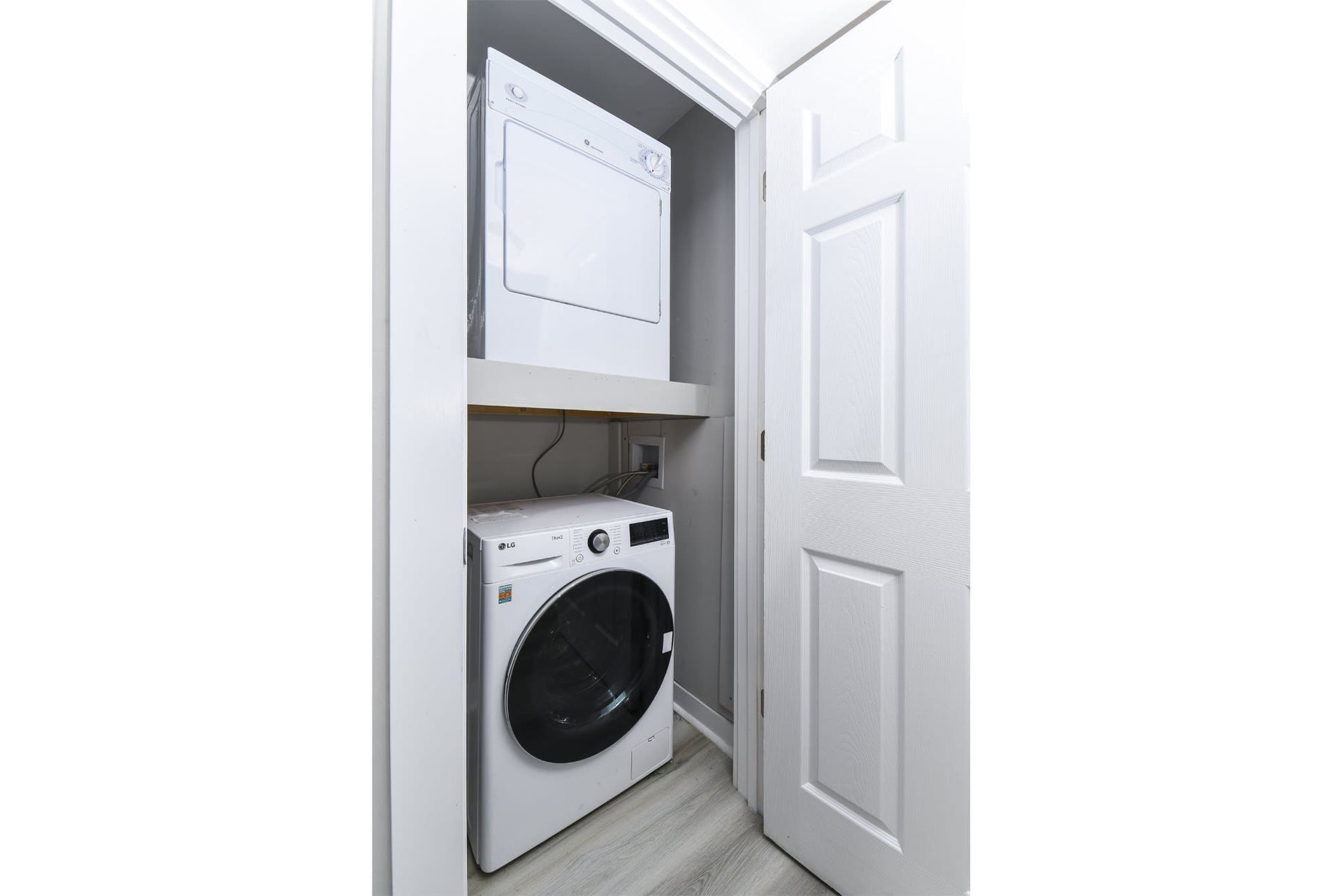 In-unit laundry closet with a stacked washer and dryer behind an open door.