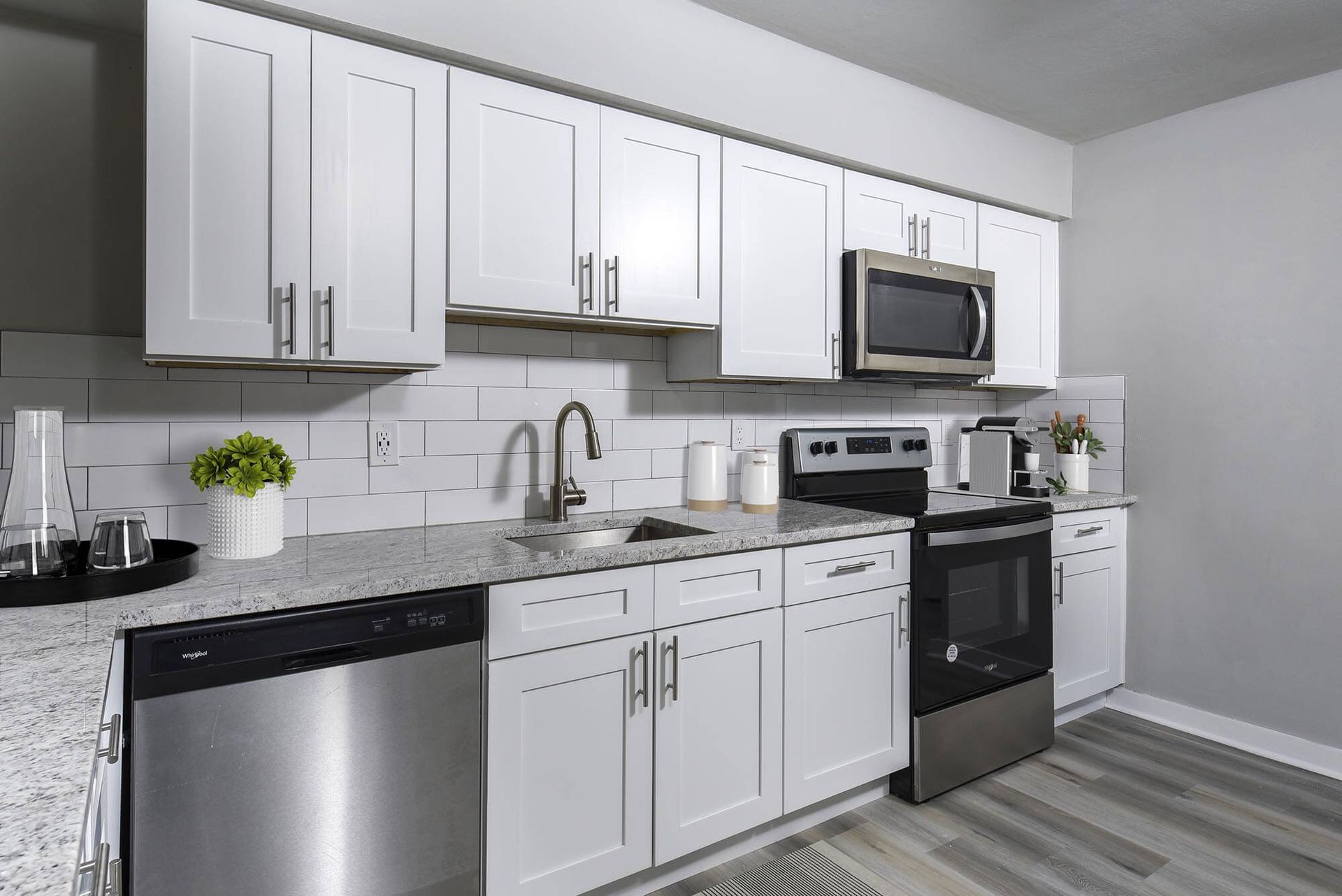 Modern kitchen with white cabinets, gray countertops, and stainless steel appliances.
