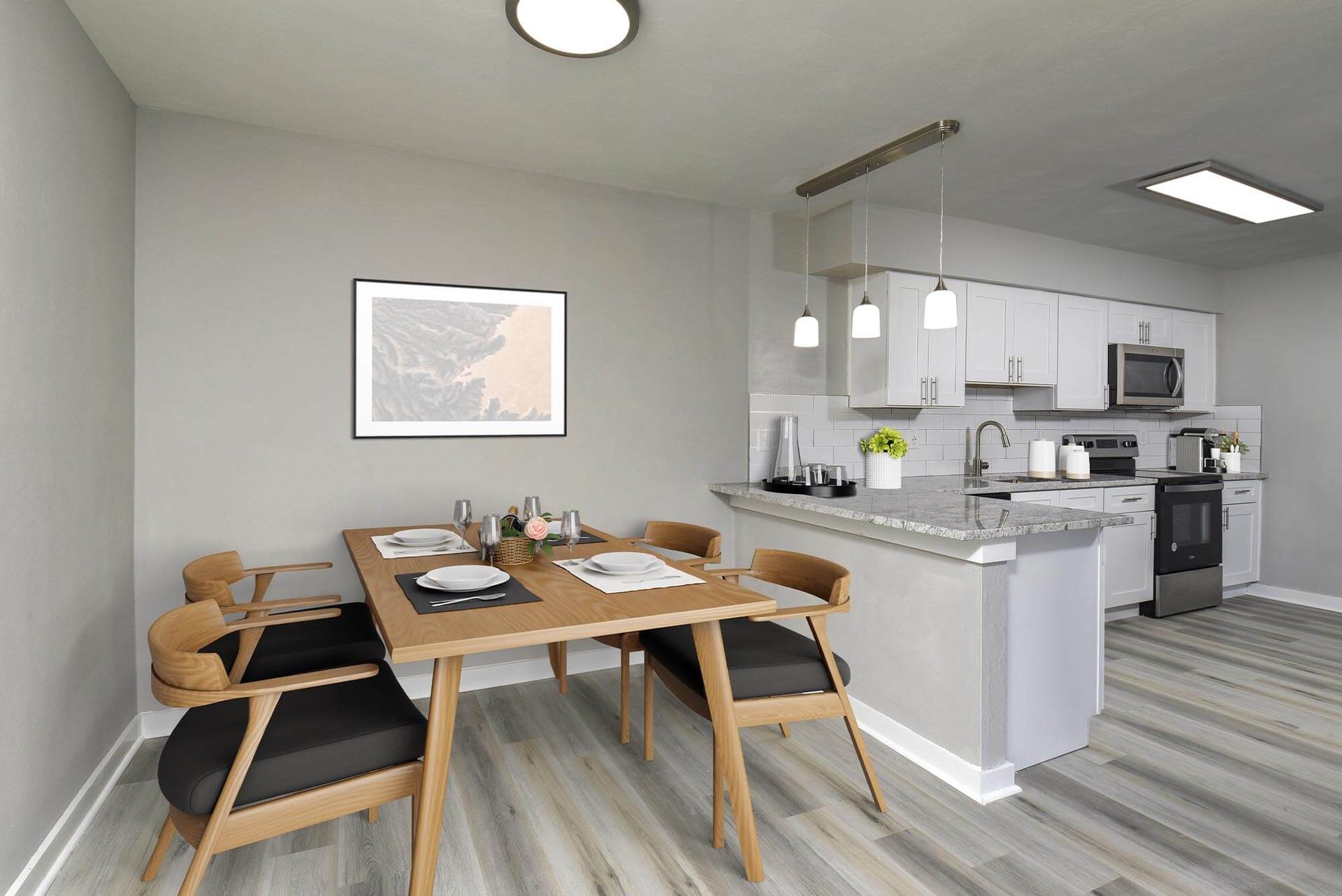 Open-concept dining area with a wooden table, four chairs, and a modern kitchen with white cabinets and stainless-steel appliances.