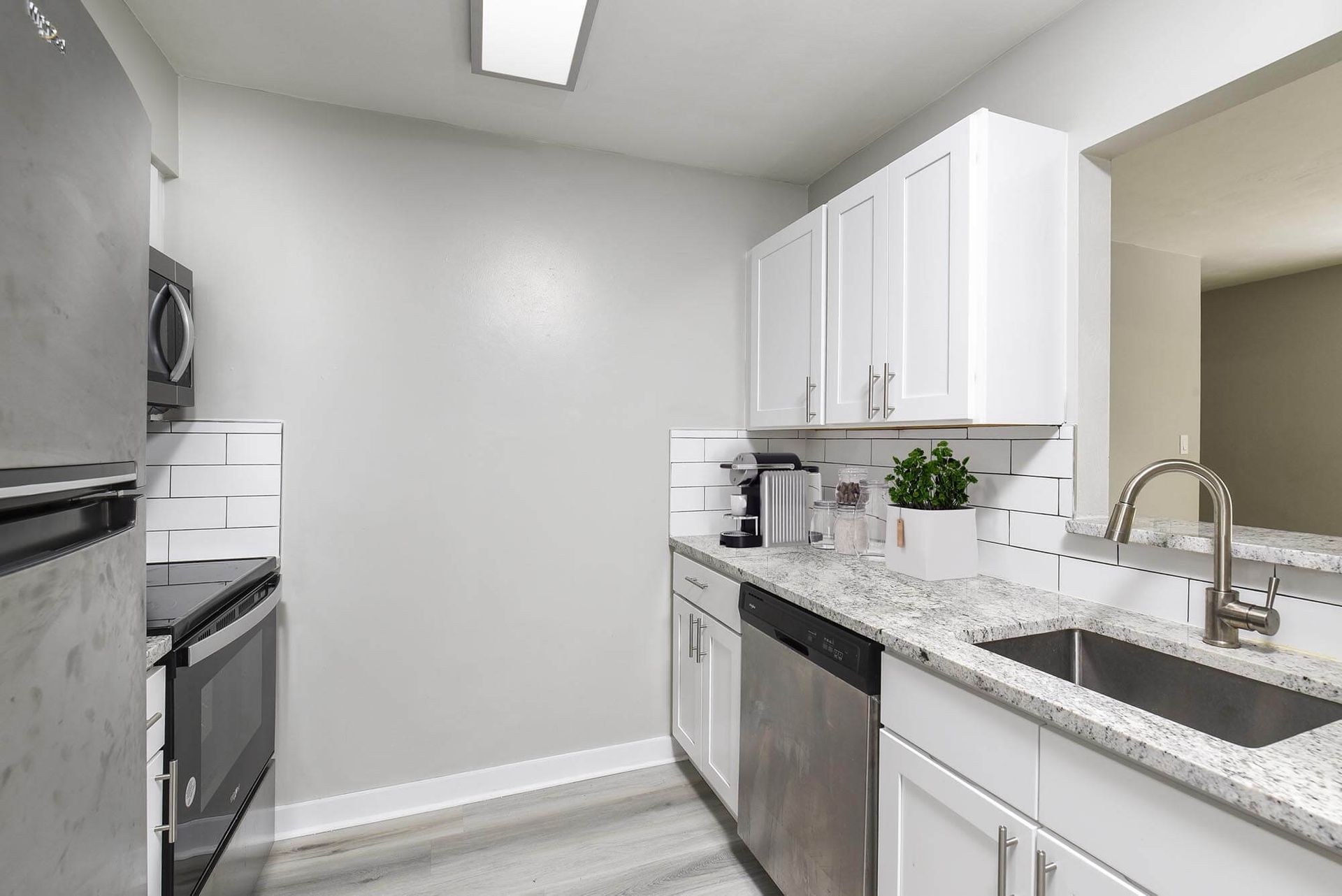 Kitchen in an apartment with white cabinets, granite countertops, and stainless steel appliances.