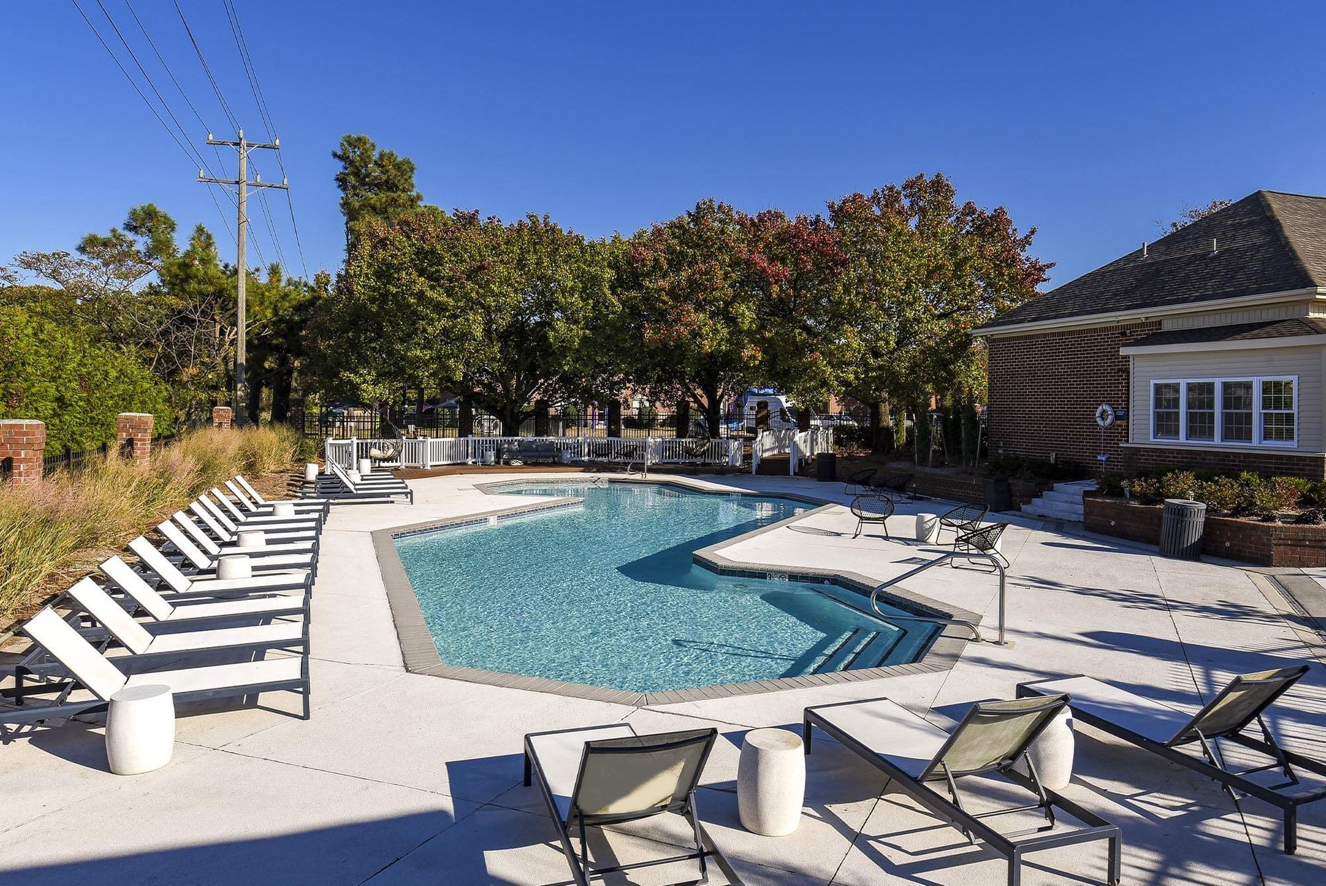 Outdoor apartment pool area with lounge chairs and surrounding trees