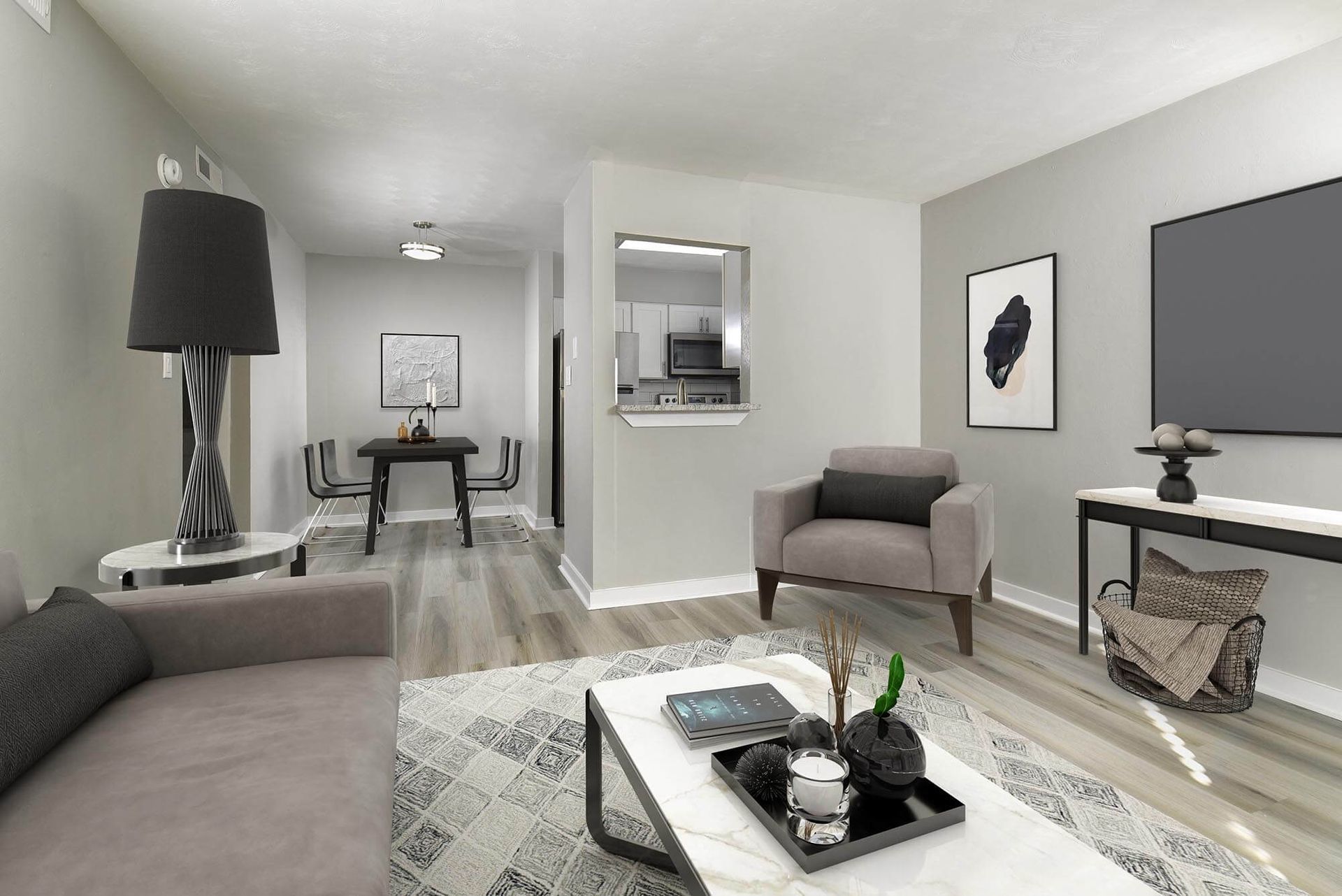 Open-concept living room with gray walls, a sofa, chairs, and a sightline to the kitchen.