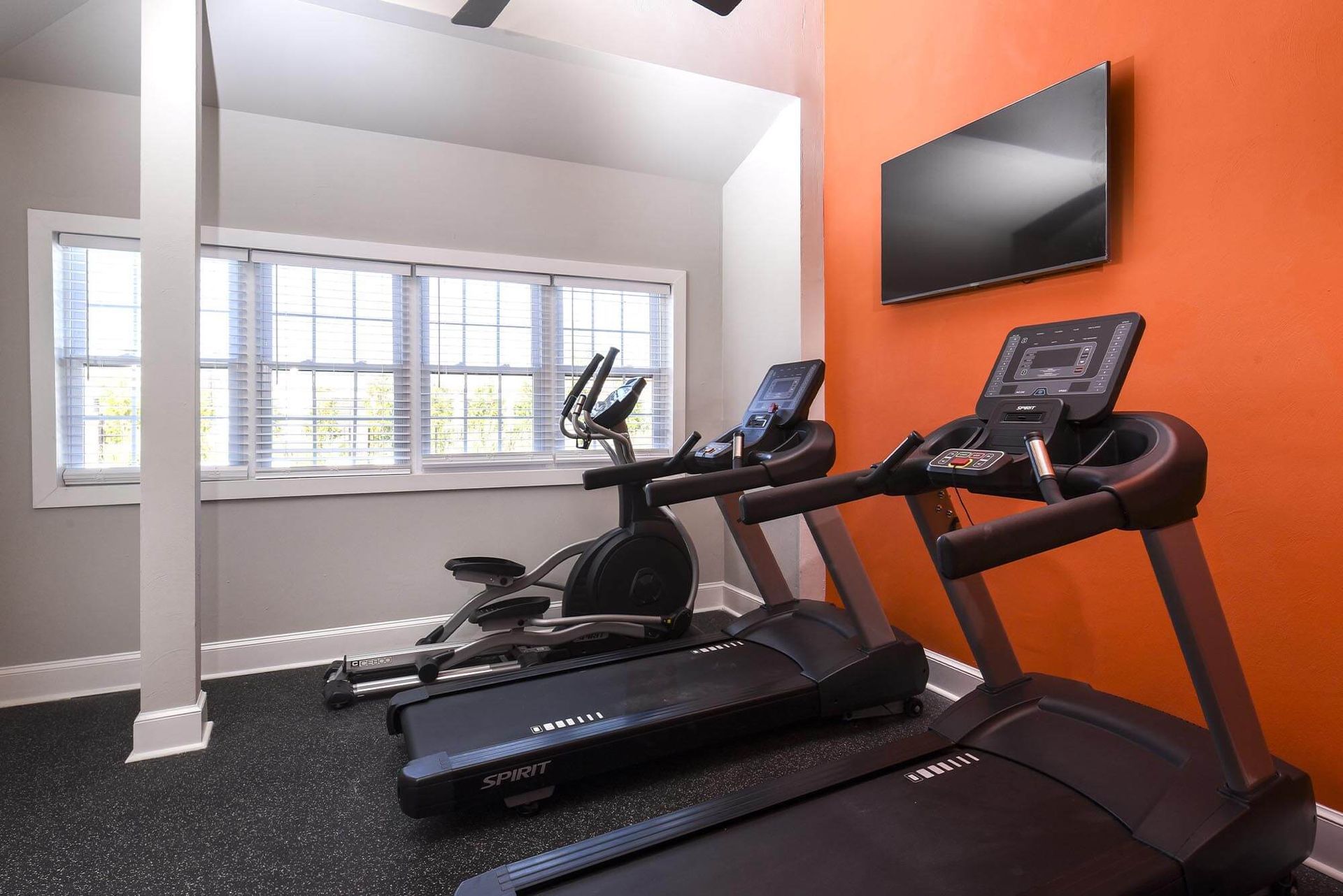 Fitness center with treadmills and an elliptical by a window.