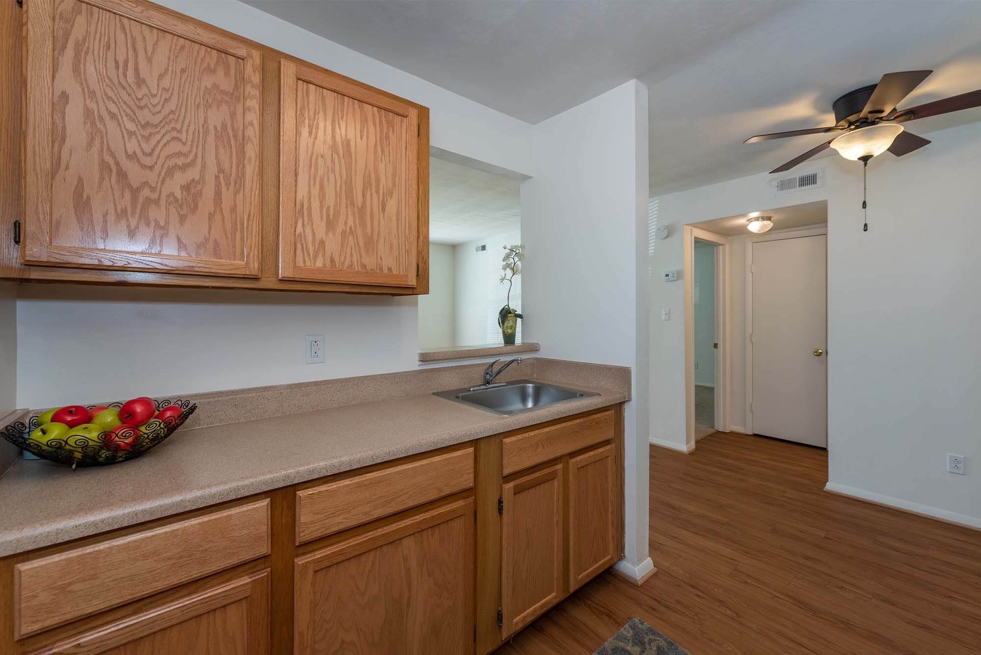 Kitchen with oak cabinets, beige countertops, a stainless sink, and wood flooring.