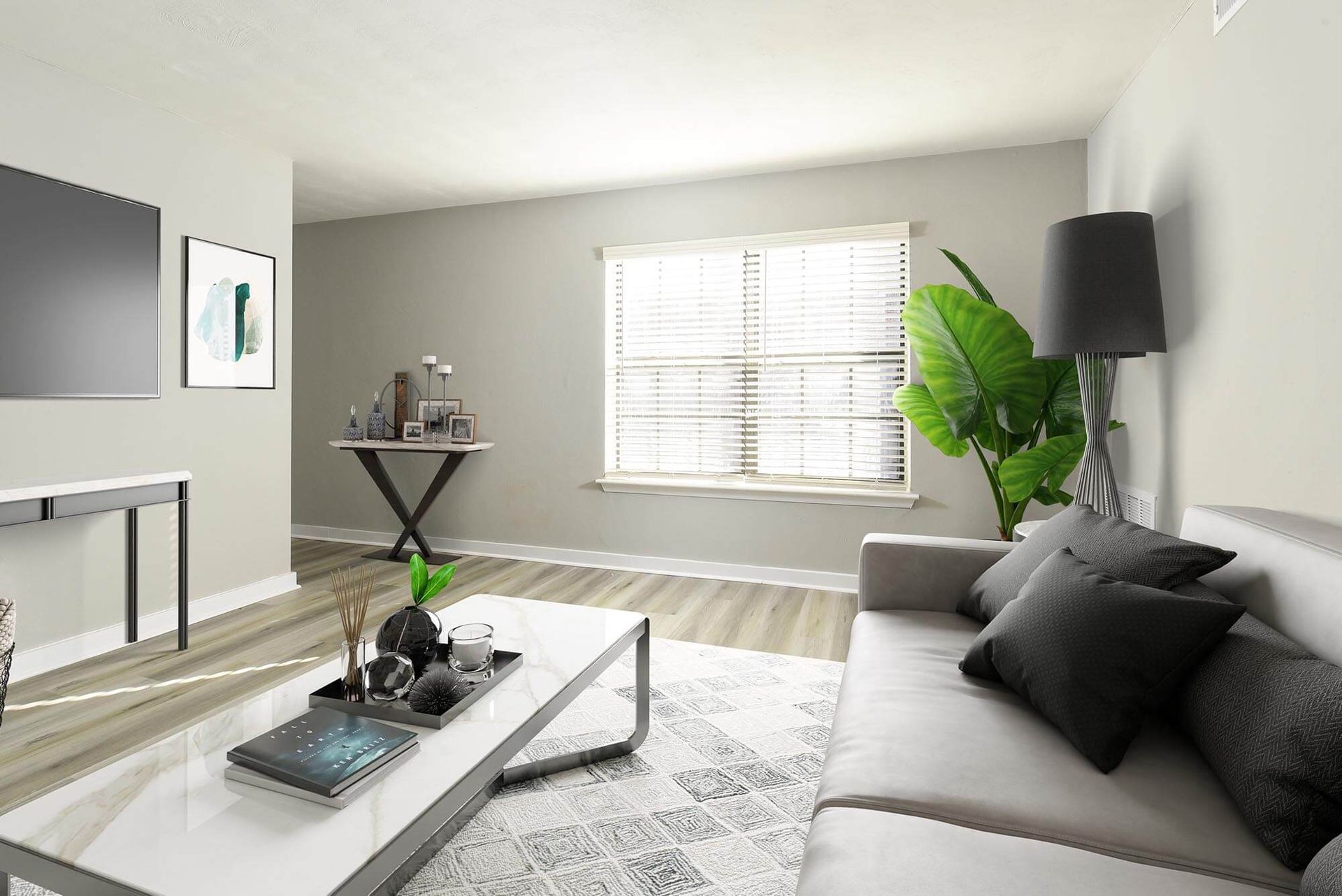 Living room with a gray sofa, coffee table, plant, and large window with blinds.